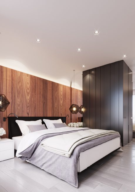 A modern bedroom with sleek black cabinets, wood-paneled walls, and recessed ceiling lighting.