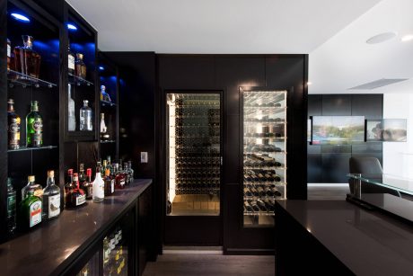 Well-appointed bar area with sleek, dark cabinetry, wine storage, and ample liquor display.