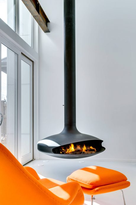 Sleek, suspended fireplace with a modern, minimalist design, complementing the vibrant orange furnishings.