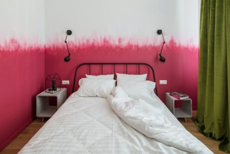 Vibrant ombre-painted walls, black metal bed frame, and minimal side tables create a modern, cozy bedroom.