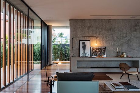 Minimalist modern living room with floor-to-ceiling glass doors, concrete wall, and sleek furnishings.