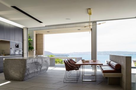 Spacious modern kitchen and dining area with panoramic ocean view and minimalist design.