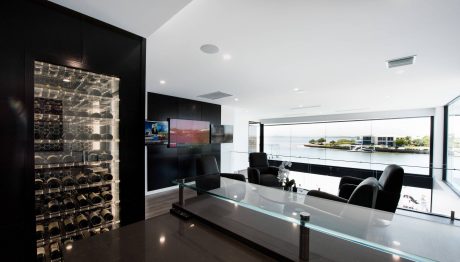 Sleek, modern interior with glass walls, built-in wine storage, and large screen.