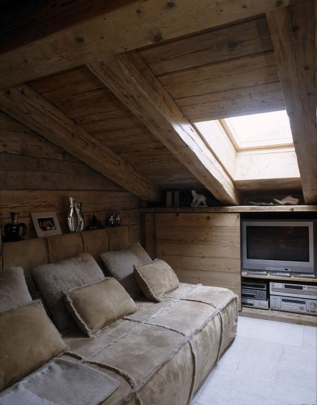 Rustic wooden cabin interior with cozy sofa, shelves, and skylights.