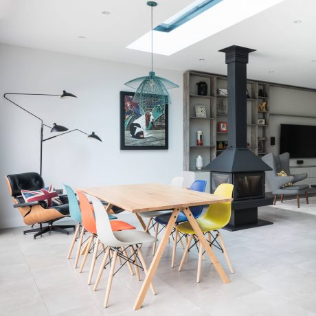 An open-concept living space with a modular dining set, pendant lights, and a wood-burning stove.
