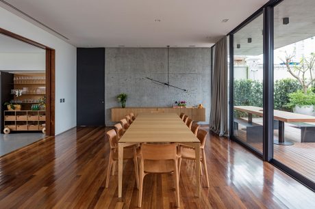 Large open-concept dining area with wooden table, chairs, and concrete wall accents.