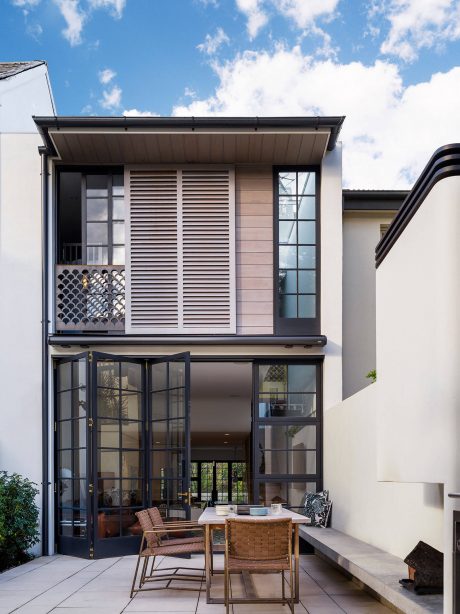 Modern exterior with slatted wood panels, large glass doors, and outdoor seating area.