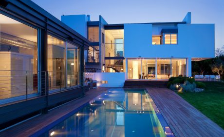 Striking contemporary architecture with sleek glass walls, pool, and landscaping.