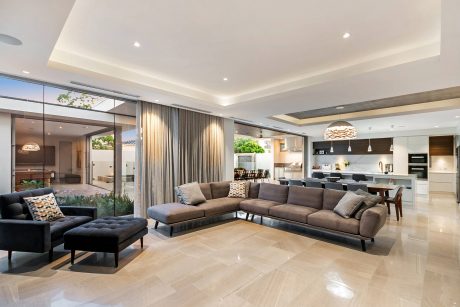 Spacious open-plan living area with modern furnishings, large sectional sofa, and glass walls.