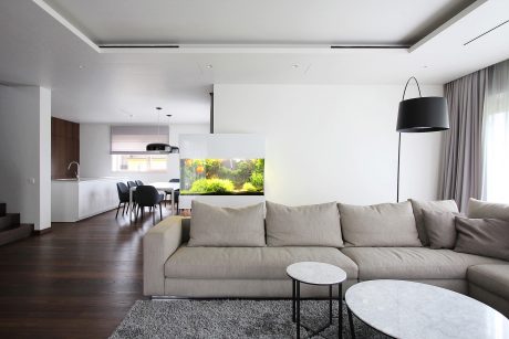 Spacious, modern living room with large gray sofa, marble coffee tables, and aquarium.