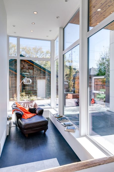 Airy living room with large windows overlooking a lush backyard and wooden accents.