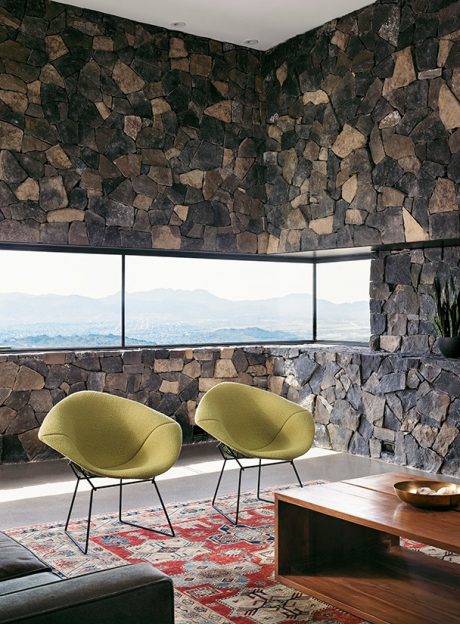 Cozy modern living room with rustic stone walls, plush seating, and panoramic views.