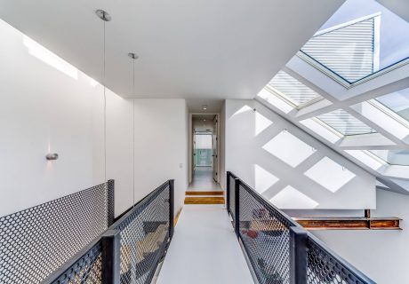 Bright, modern hallway with glass skylights and black metal railings.