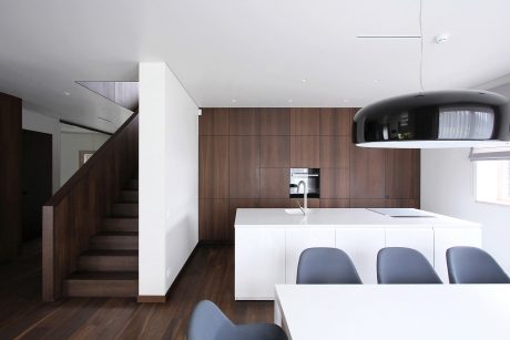 Sleek, modern kitchen with wooden cabinetry, white countertops, and pendant lighting.