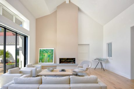 Spacious living room with high ceilings, fireplace, and modern furniture arrangement.
