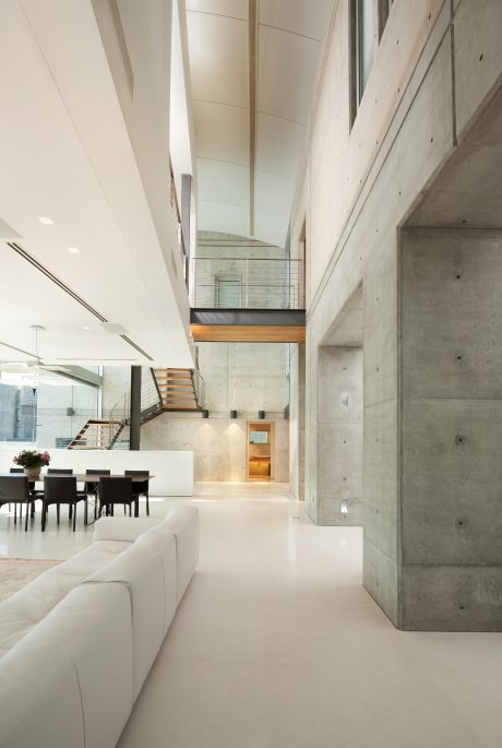 A modern, minimalist interior featuring concrete walls, glass panels, and wood accents.