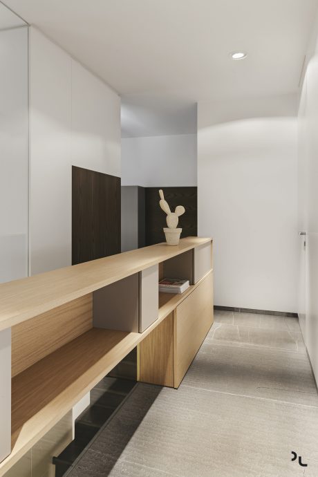 Sleek, modern hallway with minimalist wooden shelving, recessed lighting, and tiled flooring.