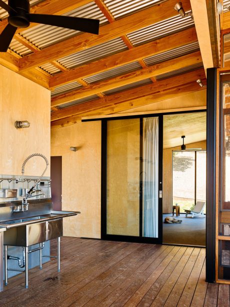 Warm-toned wood ceiling beams and sliding glass doors frame a modern kitchen.