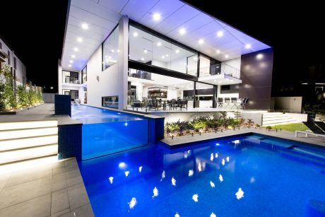 Striking modern architecture with vibrant blue pools, lush vegetation, and sleek glass walls.