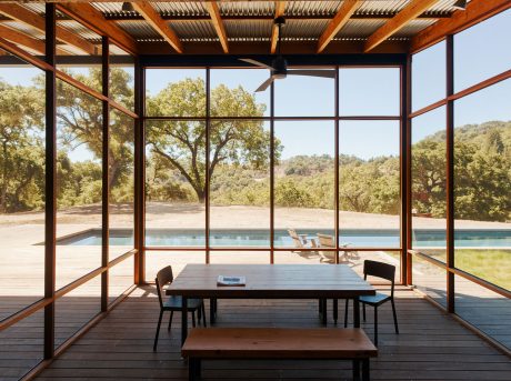 Modern rustic interior with wooden beams, glass walls, and pool view.