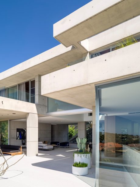 Modern architectural design with concrete structures, glass walls, and minimal landscaping elements.