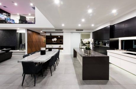 Sleek, modern kitchen and dining area featuring minimalist design, dark cabinetry, and large windows.