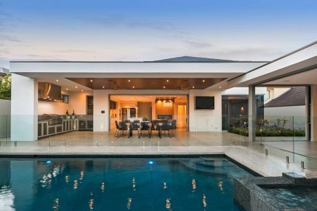 Sleek and modern home with open-plan layout, pool, and glass walls offering panoramic views.