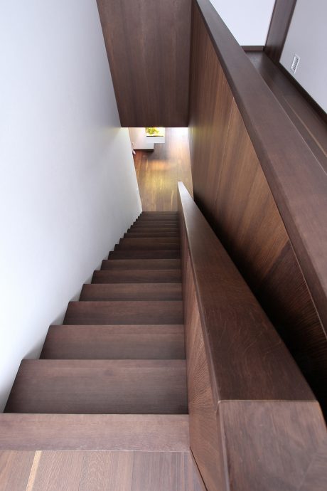 Dramatic, angular staircase with wooden steps and walls, leading to a warm, welcoming space.