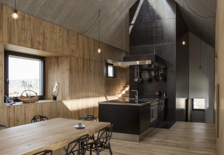 A modern wooden cabin interior with a kitchen, dining area, and industrial-style accents.