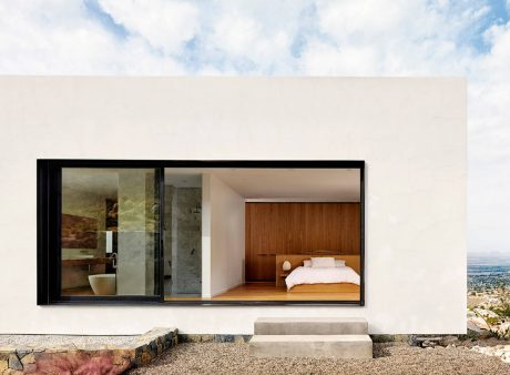 Minimalist modern architecture with floor-to-ceiling glass windows, interior wood paneling, and an en-suite bathroom.