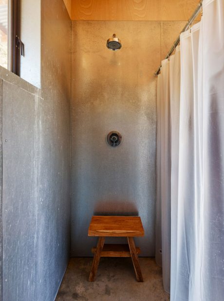 A small, rustic shower stall with a wooden bench and a curtain for privacy.