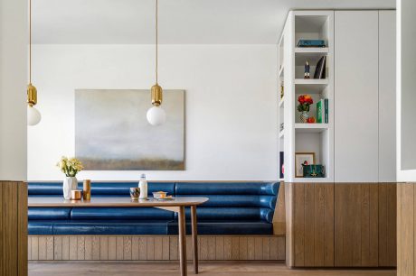 Sleek modern living space with royal blue sofa, hanging lamps, and built-in shelving.