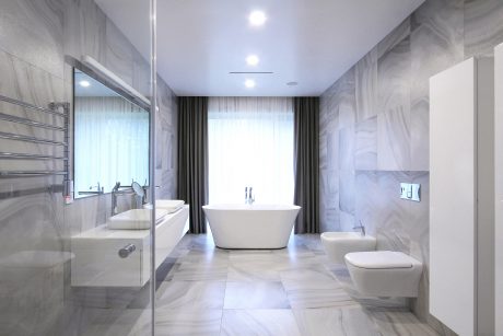 Luxurious bathroom with freestanding tub, floor-to-ceiling marble tiles, and modern fixtures.