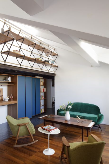 Modern living space with geometric shelving, plush green sofa, and mid-century furniture.
