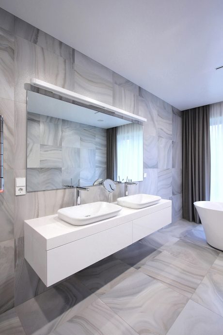 Modern bathroom design with sleek white vanity, dual sinks, and dramatic marble walls.