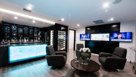 Sleek, modern lounge with a glowing bar, plush seating, and a wall-mounted TV display.