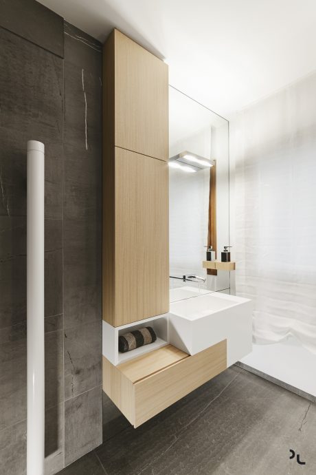 A modern bathroom with a wooden vanity, white vessel sink, and a large mirror adorned with integrated lighting.