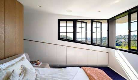 Cozy bedroom with large windows offering scenic outdoor views, modern wood paneling accents.