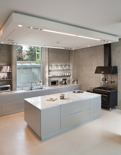 Sleek, modern kitchen with concrete walls, floating shelves, and a large central island.