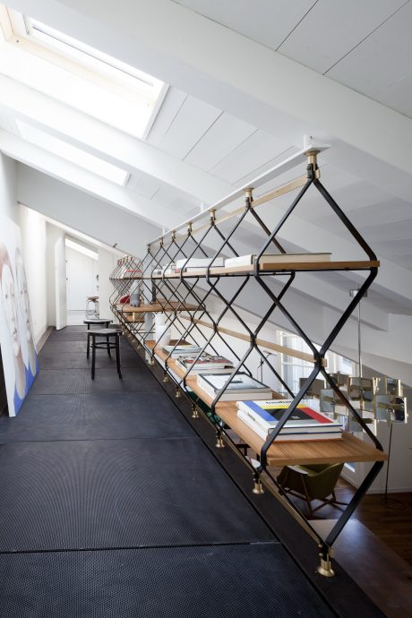 A modern, open-plan interior with a striking geometric shelving unit made of metal and wood.