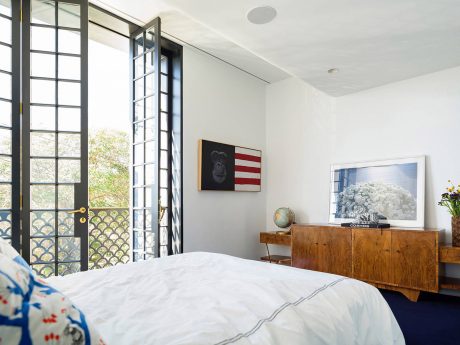 Spacious bedroom with large windows, stylish furniture, and modern art decor.