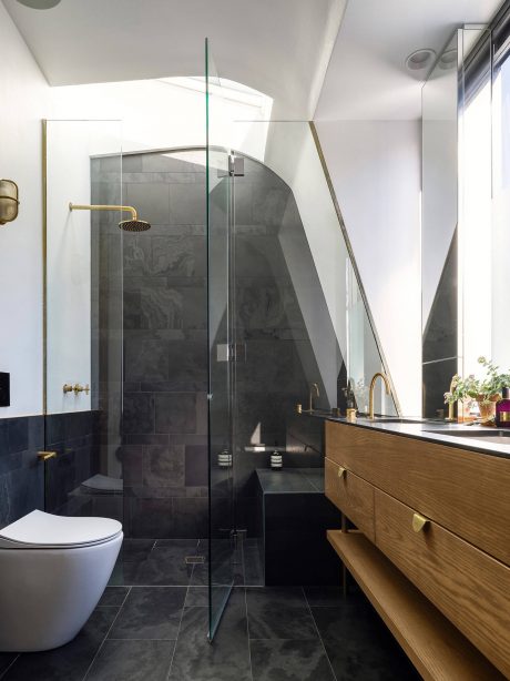 Elegant bathroom with sleek glass enclosure, stone tiles, and wooden vanity.