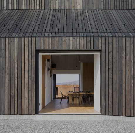 Wooden exterior with large window frame opening to an interior dining area.