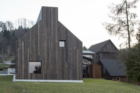 Modern wooden cabin nestled in forested landscape, featuring clean architectural lines.