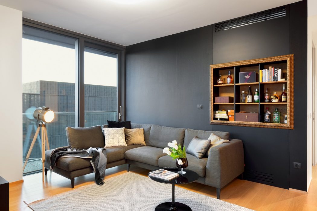 Stylish living room with dark walls, cozy sectional sofa, and custom built-in shelving.