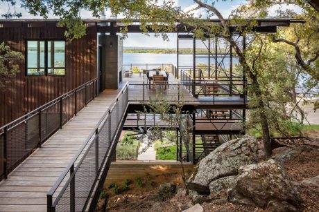 Striking modern cabin-like structure surrounded by nature, featuring extensive decking.