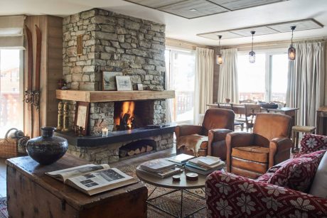 Rustic living room with stone fireplace, wooden accents, and cozy furnishings.
