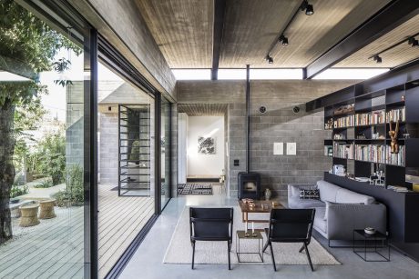 Minimalist living space with concrete walls, wooden ceiling, and large glass doors leading to a deck.
