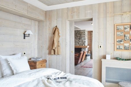 Cozy cabin interior with rustic wood paneling, stone fireplace, and warm textiles.