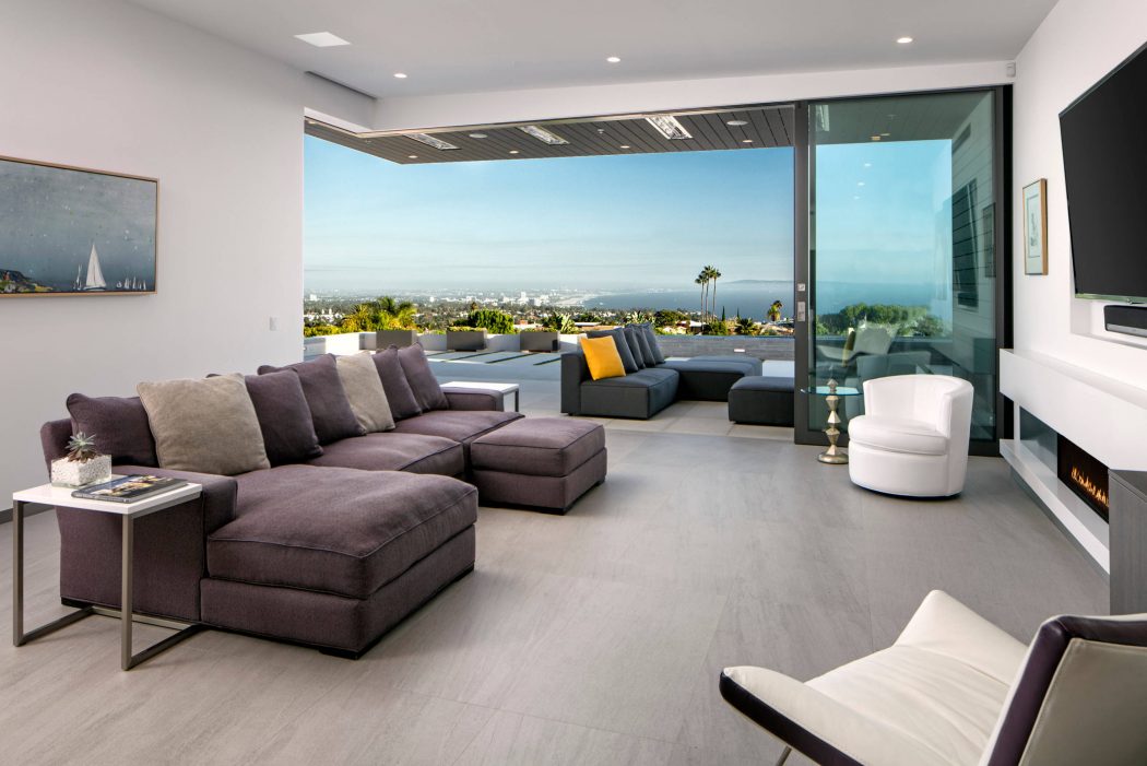Modern open-concept living room with floor-to-ceiling windows, plush seating, and scenic view.